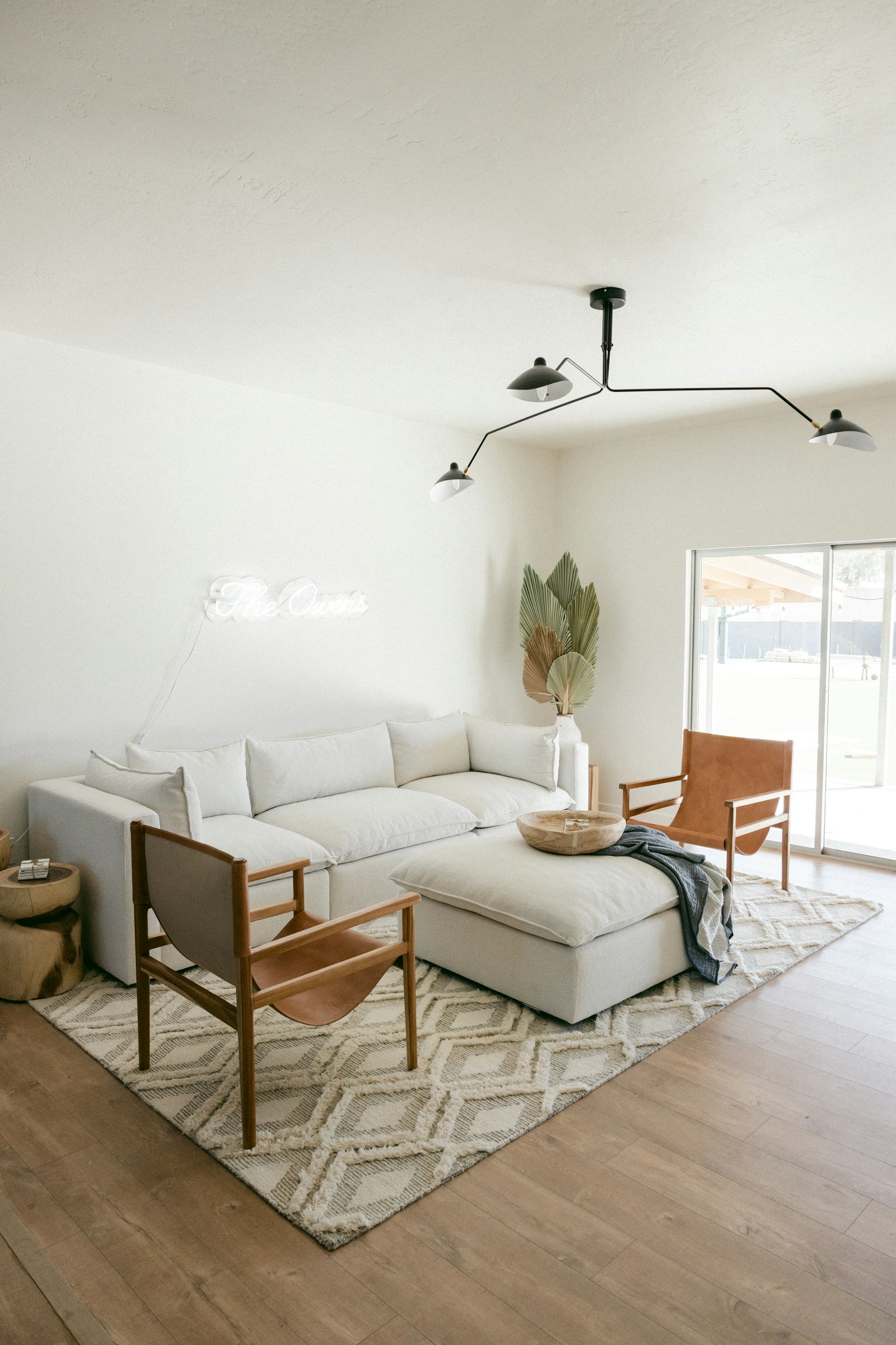Cream sectional sofa in a bright room with oak floor and tan-leather sling chairs